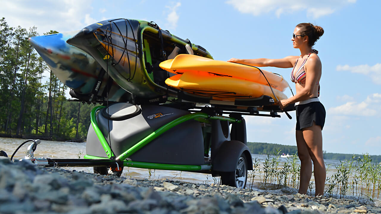 woman putting kayak on top kayak trailer