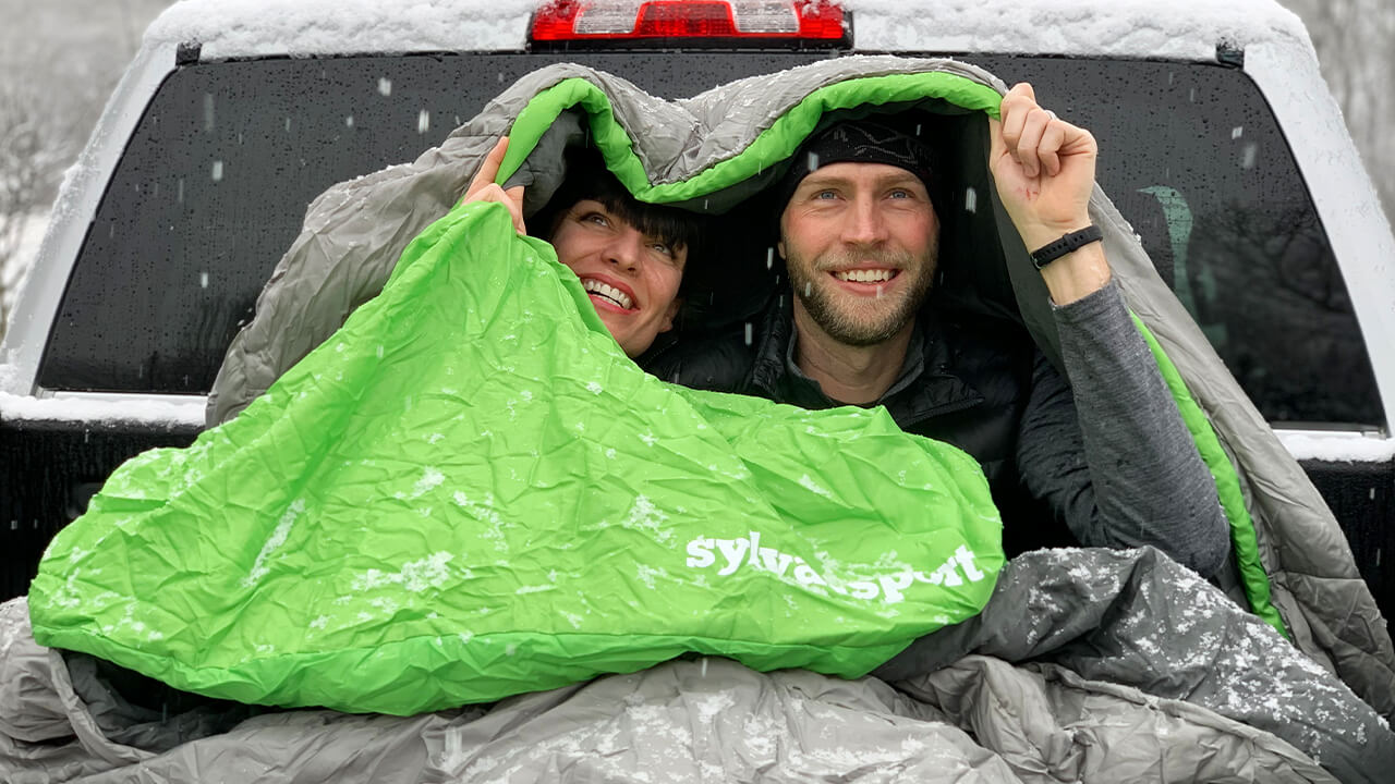 couple using sleeping bag outside during snow