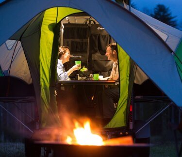 couple inside Go camper with fire pit outside