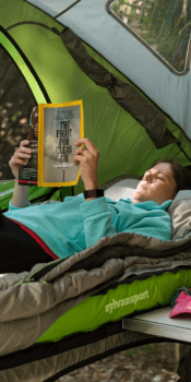 woman lying down reading book mattress camp GO camping trailer
