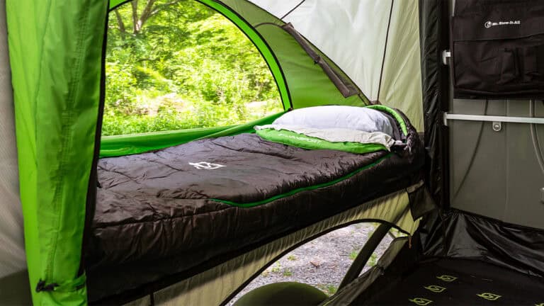 A comfortable sleeping area inside a SylvanSport camping tent with a view of lush green trees.