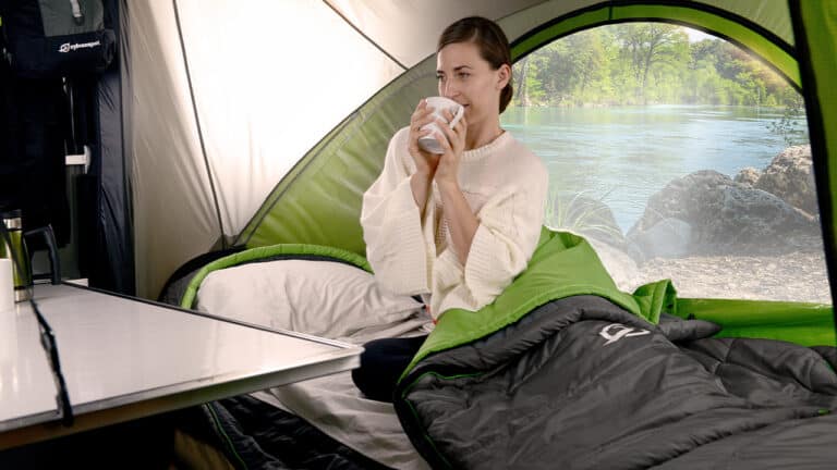 Enjoying a peaceful moment inside a SylvanSport camper near a river, perfect for outdoor adventures.