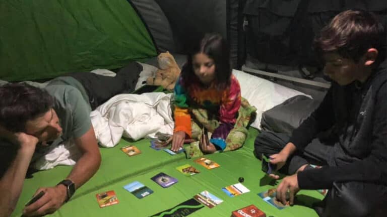 Kids playing card game inside a SylvanSport camping tent.