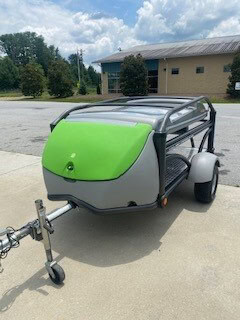Green and gray SylvanSport trailer with black frame and roof rack.