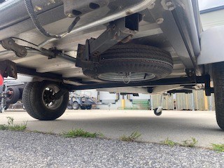 Underneath view of SylvanSport camping trailer showing spare tire and chassis.