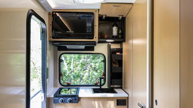 Compact kitchen area inside SylvanSport VIRE travel trailer with microwave and storage.