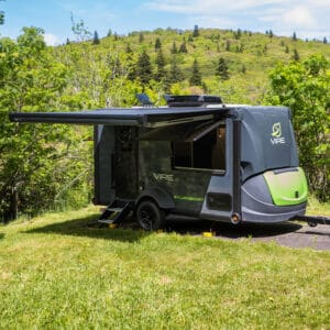 SylvanSport VIRE travel trailer parked in a lush green outdoor setting.