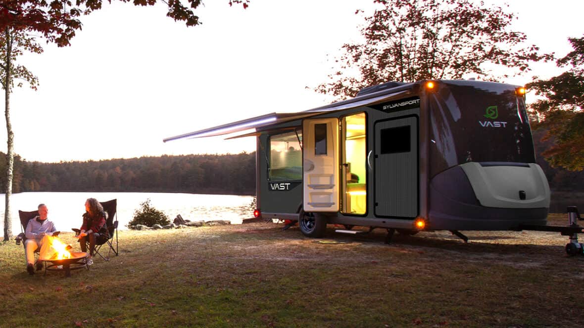 SylvanSport VAST camper trailer parked by a lake at sunset with people relaxing nearby.