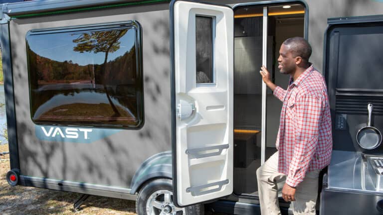 Man entering SylvanSport VAST camper trailer in outdoor setting.