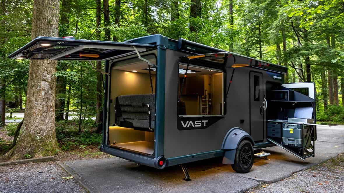 VAST Travel Trailer by SylvanSport in a forest setting with open side and rear doors.