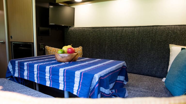 Interior of SylvanSport VIRE travel trailer with dining area and TV.
