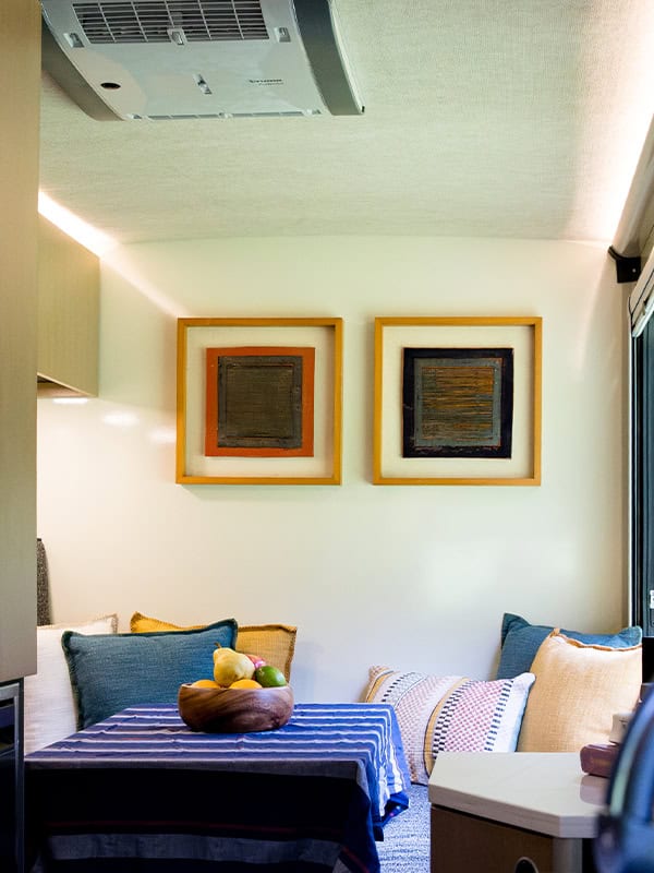 Cozy living area inside a SylvanSport VIRE Travel Trailer with colorful cushions and wall art.