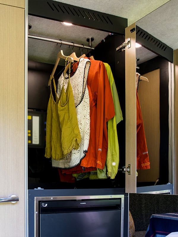 Closet with hanging outdoor clothing and jackets inside SylvanSport VIRE Travel Trailer.