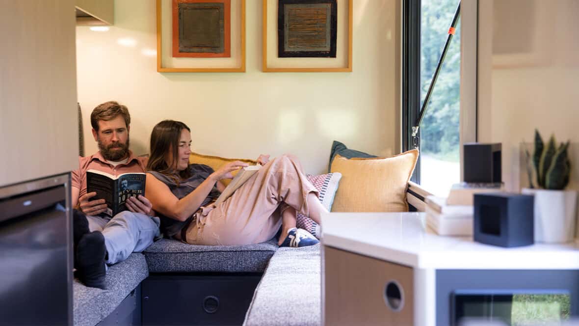 Couple relaxing on a SylvanSport camper sofa in a cozy living space.