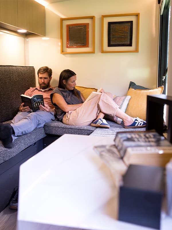 Couple relaxing on a sofa inside the SylvanSport VIRE travel trailer.