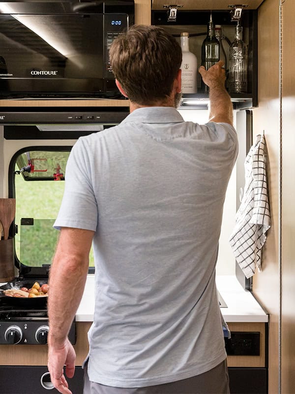 Man reaching for a bottle in a modern kitchen with SylvanSport branding.