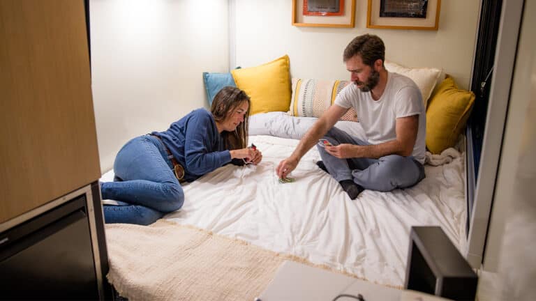 Young woman and man playing a game on bed in cozy room.